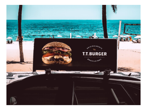Topo do funil marketing: imagem de um anúncio de uma hamburgueria no visor em cima de um carro passando em frente a praia