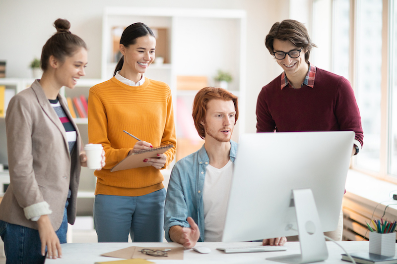 Automacao de marketing para agências: imagem de quatro pessoas no escritório conversando e olhando para a tela do computador