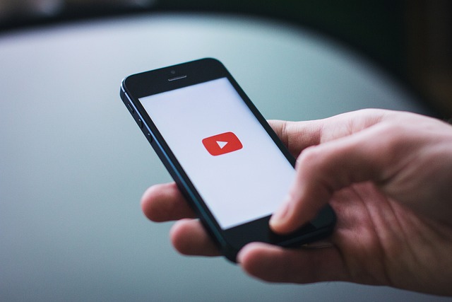 Tráfego pago: imagem de uma mão branca segurando um celular, mostrando o logo do Youtube.