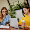 Artificial Intelligence Site: image of two young women, one blonde and the other Asian, focused on their work.