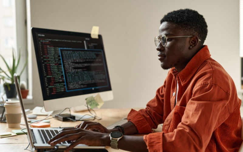 Teste de Turing: imagem de um homem negro com uma camisa laranja, olhando para os códigos em seu computador
