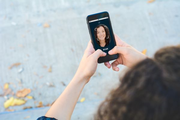 Examples of Artificial Inteligence: overhead image of a woman using facial recognition on her cell phone