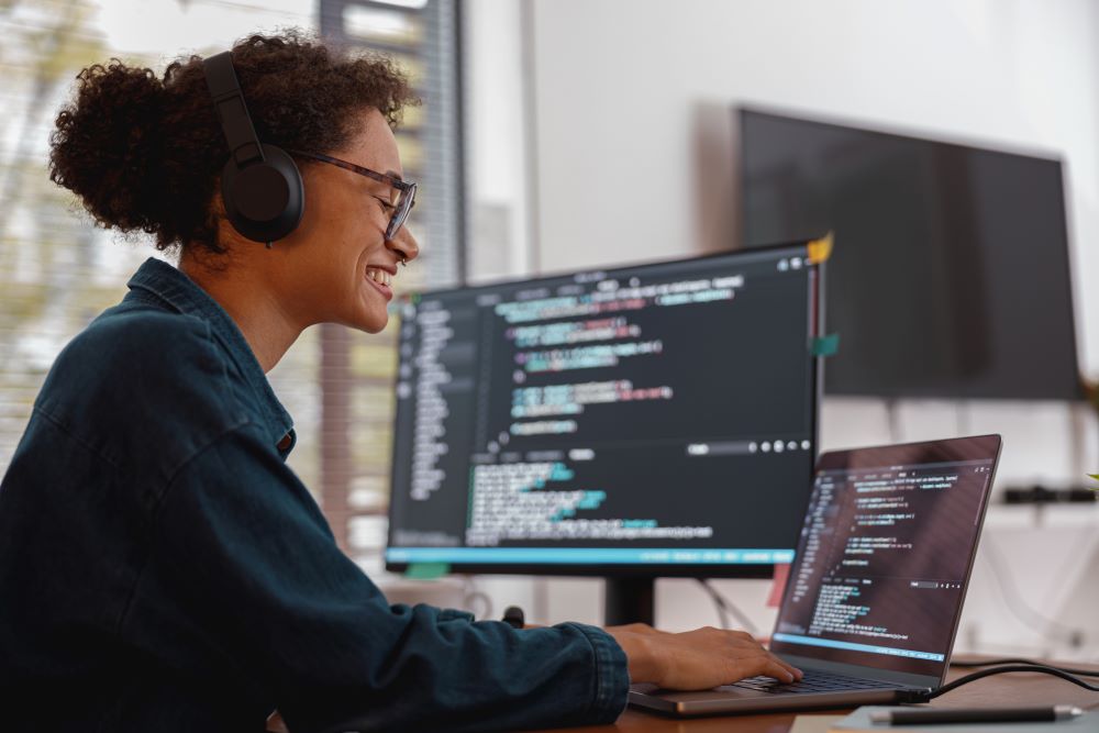 Data and  AI: smiling black female software developer working on her computer.
